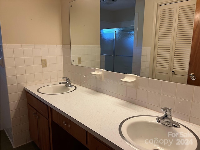 bathroom with vanity, tile walls, and a shower with shower door