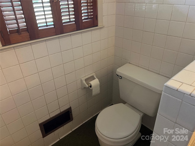 bathroom with tile walls and toilet