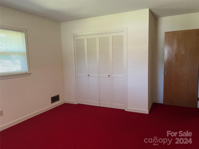 unfurnished bedroom with a closet, carpet flooring, and a textured ceiling