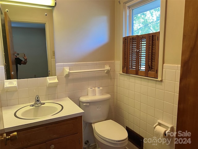 bathroom with tile walls, vanity, and toilet