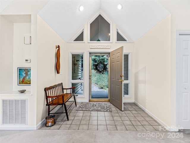 carpeted foyer featuring high vaulted ceiling