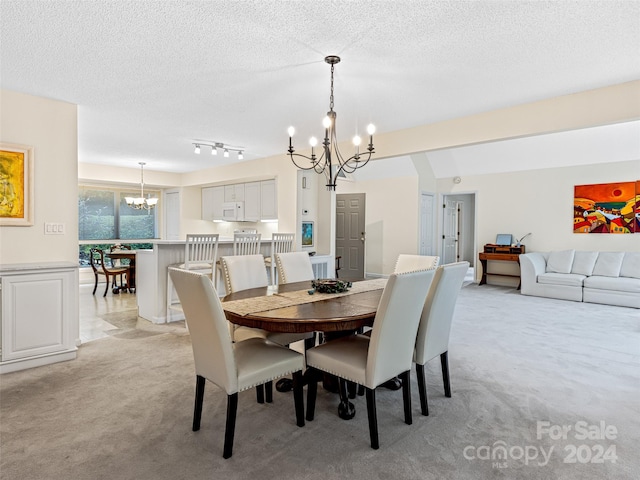 dining room featuring a notable chandelier, a textured ceiling, light colored carpet, and track lighting