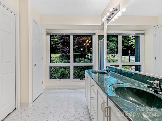 bathroom with tile patterned flooring, double sink vanity, and a wealth of natural light