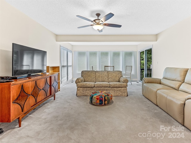 carpeted living room with a textured ceiling and ceiling fan