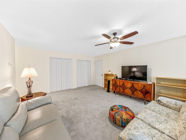 living room with light carpet, a textured ceiling, and ceiling fan