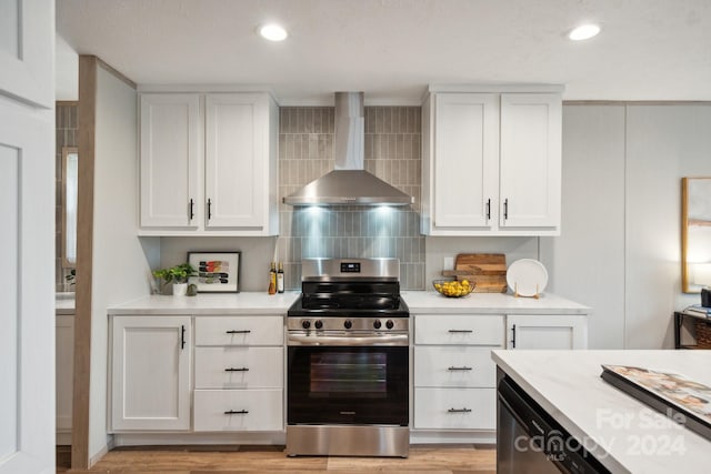 kitchen with decorative backsplash, gas range, wall chimney exhaust hood, and white cabinets