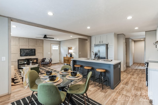 dining room with sink, light wood-type flooring, and ceiling fan