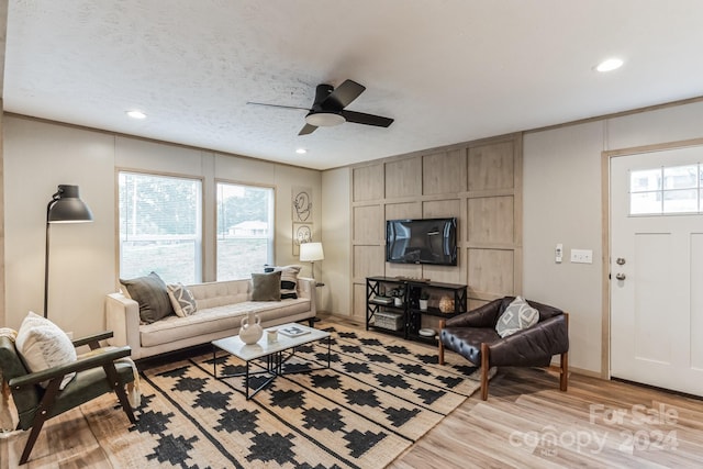 living room featuring light hardwood / wood-style flooring, a textured ceiling, and ceiling fan