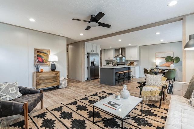 living room featuring sink, a textured ceiling, ceiling fan, and light hardwood / wood-style floors