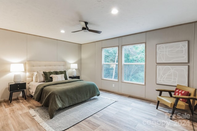 bedroom with light hardwood / wood-style flooring, ornamental molding, and ceiling fan