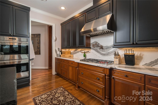 kitchen with dark wood-type flooring, backsplash, stainless steel appliances, light stone counters, and ornamental molding