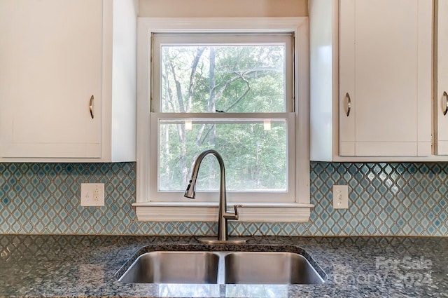 kitchen featuring white cabinetry, a wealth of natural light, dark stone counters, and sink