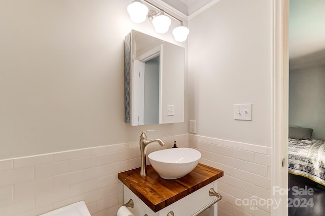 bathroom with vanity, crown molding, and tile walls