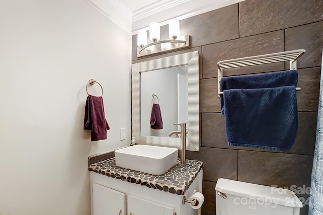 bathroom with vanity, toilet, crown molding, and tile walls