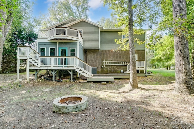 back of property with a fire pit, a balcony, central air condition unit, and a wooden deck