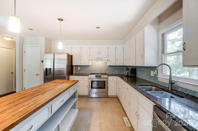 kitchen with hanging light fixtures, sink, appliances with stainless steel finishes, white cabinetry, and butcher block counters