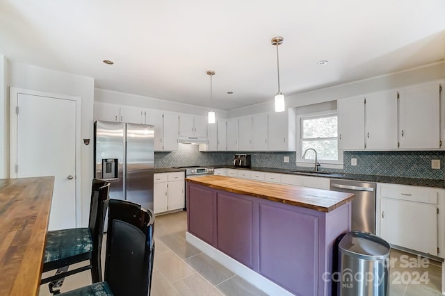 kitchen featuring stainless steel appliances, white cabinetry, butcher block counters, and sink