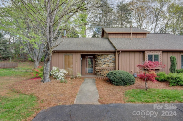 view of front of property featuring board and batten siding, stone siding, and a shingled roof