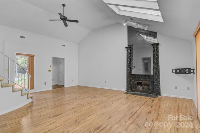 unfurnished living room with visible vents, wood finished floors, a high end fireplace, a skylight, and stairs