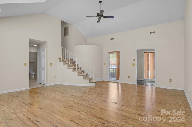 unfurnished living room with stairway, high vaulted ceiling, visible vents, and wood-type flooring