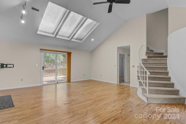 unfurnished living room featuring visible vents, baseboards, lofted ceiling with skylight, stairs, and light wood-type flooring