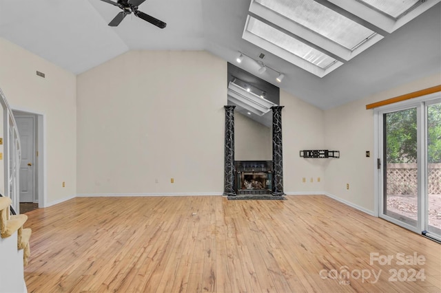 unfurnished living room with a premium fireplace, wood-type flooring, baseboards, and a skylight