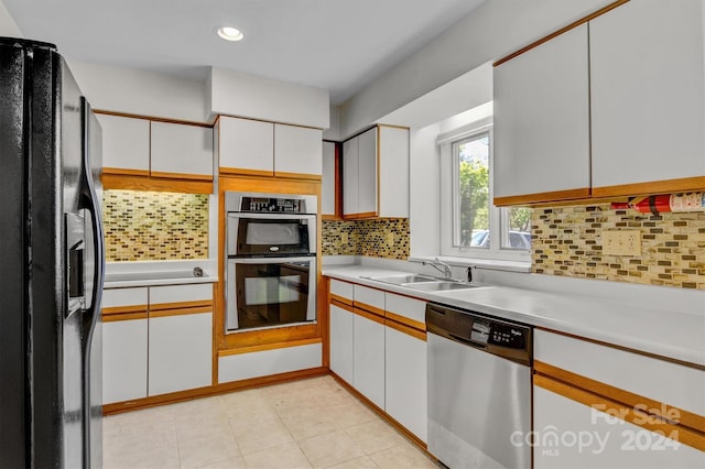 kitchen with a sink, decorative backsplash, light countertops, white cabinets, and stainless steel appliances