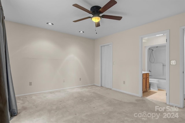 unfurnished bedroom with a ceiling fan, light colored carpet, baseboards, and connected bathroom