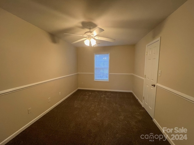 spare room featuring ceiling fan and dark colored carpet