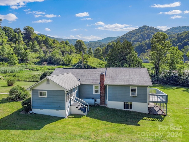 back of property with a lawn and a deck with mountain view