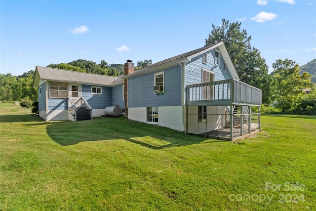 back of property featuring cooling unit, a wooden deck, and a lawn