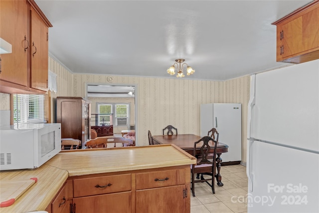 kitchen with light tile patterned floors, a notable chandelier, and white appliances