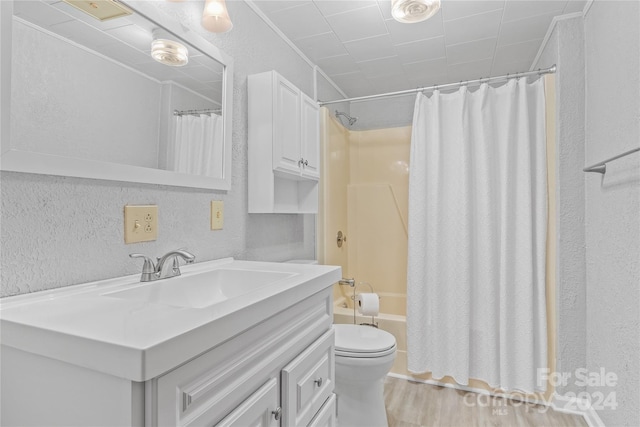 full bathroom with hardwood / wood-style flooring, vanity, shower / tub combo, and toilet