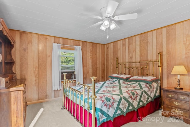 bedroom featuring ceiling fan, wooden walls, and light carpet