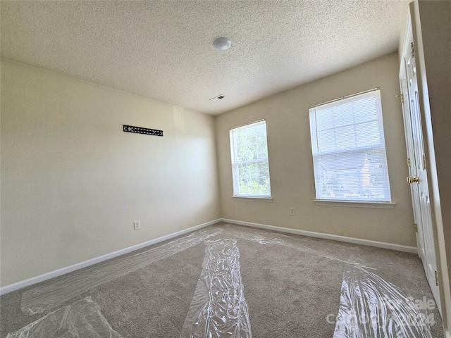 carpeted empty room featuring a textured ceiling