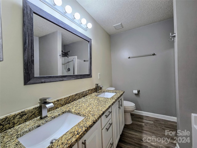 bathroom with hardwood / wood-style floors, double sink vanity, a shower, a textured ceiling, and toilet