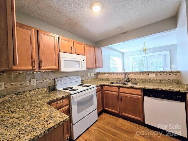 kitchen featuring sink, white appliances, a textured ceiling, and light hardwood / wood-style flooring