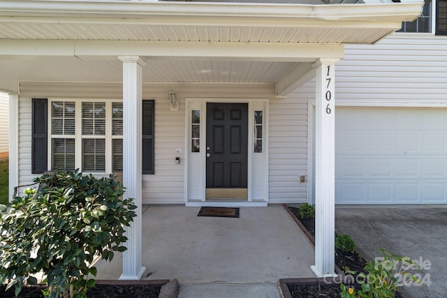 view of exterior entry with a garage and a porch