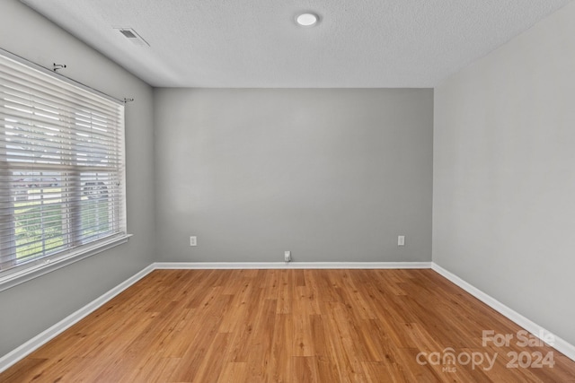 unfurnished room with light hardwood / wood-style flooring and a textured ceiling