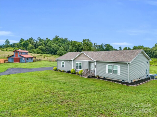 ranch-style home with central AC unit, a front lawn, and an outdoor structure