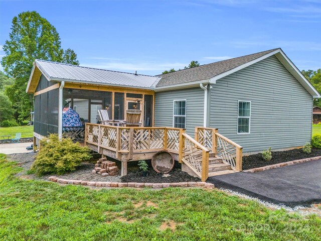 view of front of property with a sunroom, a front yard, and a deck