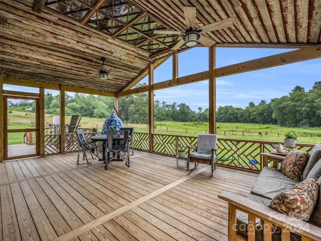 unfurnished sunroom featuring lofted ceiling, a rural view, and ceiling fan