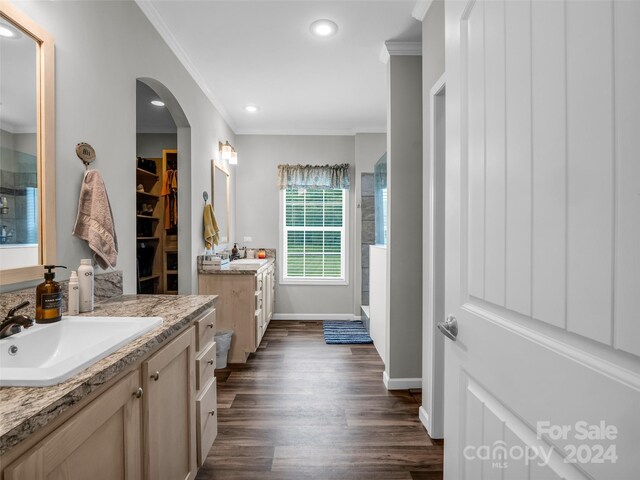 bathroom with double sink vanity, ornamental molding, and hardwood / wood-style flooring