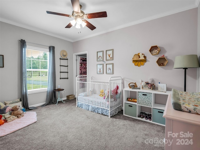 bedroom featuring ceiling fan, ornamental molding, carpet floors, and a crib