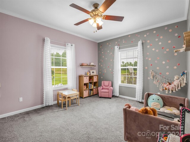 living area featuring carpet, crown molding, ceiling fan, and a healthy amount of sunlight