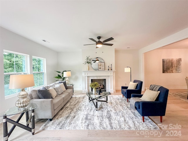 living room with ceiling fan, light wood-type flooring, and a fireplace