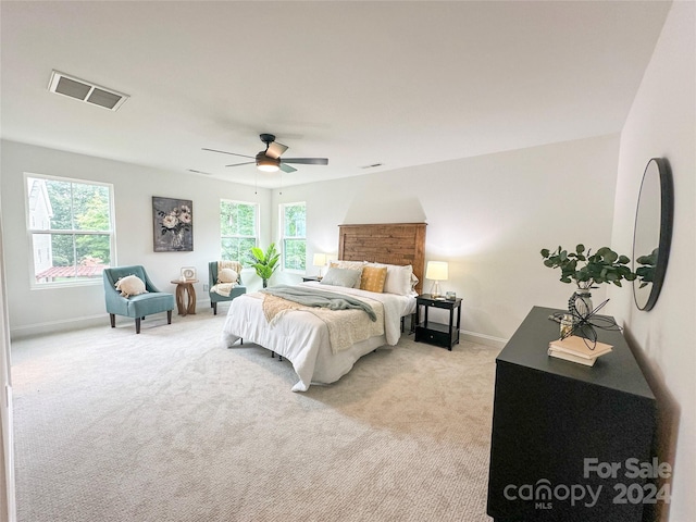 bedroom with ceiling fan, multiple windows, and light carpet