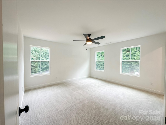 unfurnished room with plenty of natural light, light carpet, and ceiling fan