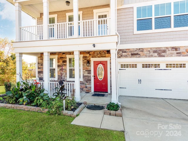 entrance to property with a yard, a garage, and a porch