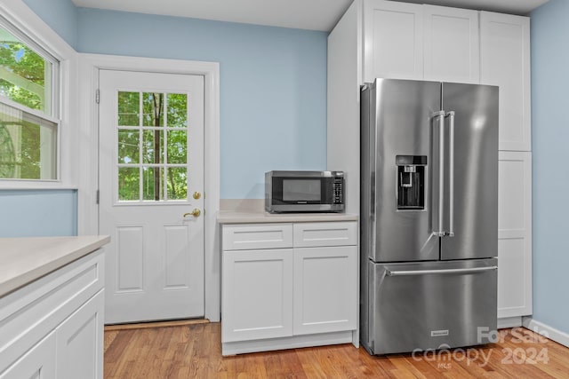 kitchen with white cabinetry, stainless steel appliances, and light hardwood / wood-style flooring